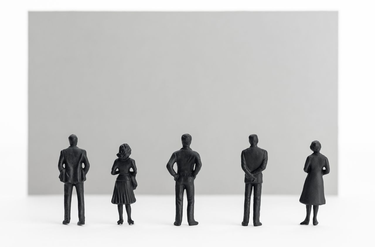 Groupe de figurines de personnes regardant une pancarte blanche vide, fond idéal pour message publicitaire