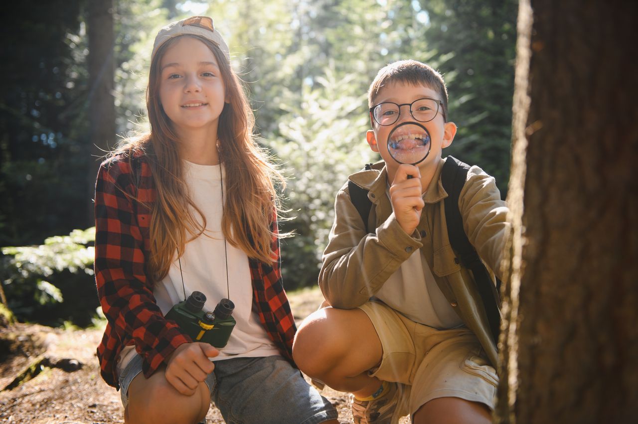 Jeunes explorateurs observant la nature en forêt avec loupe et jumelles pour l’aventure.