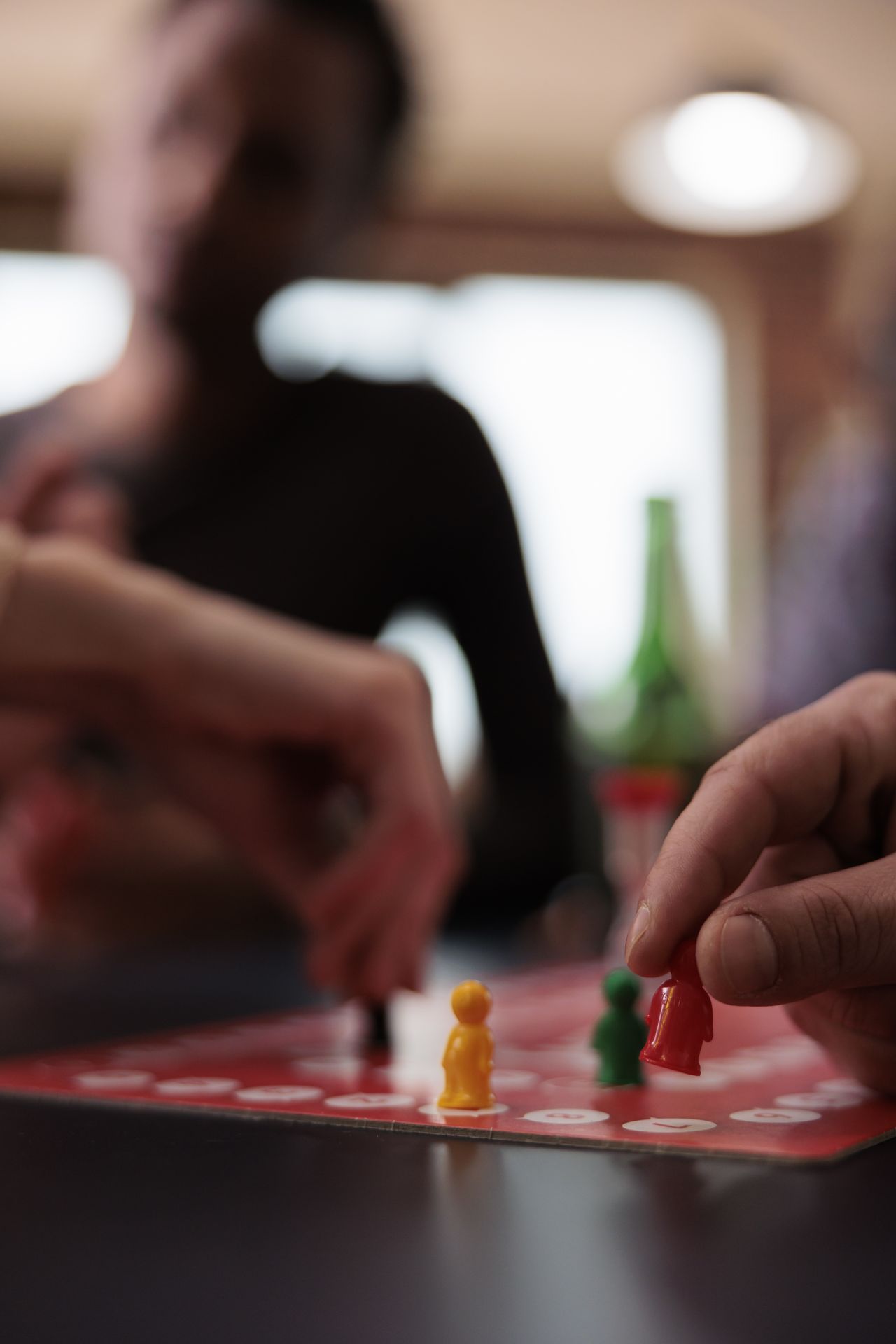 Main déplaçant une figurine sur un jeu de stratégie en société, entre amis dans le salon.