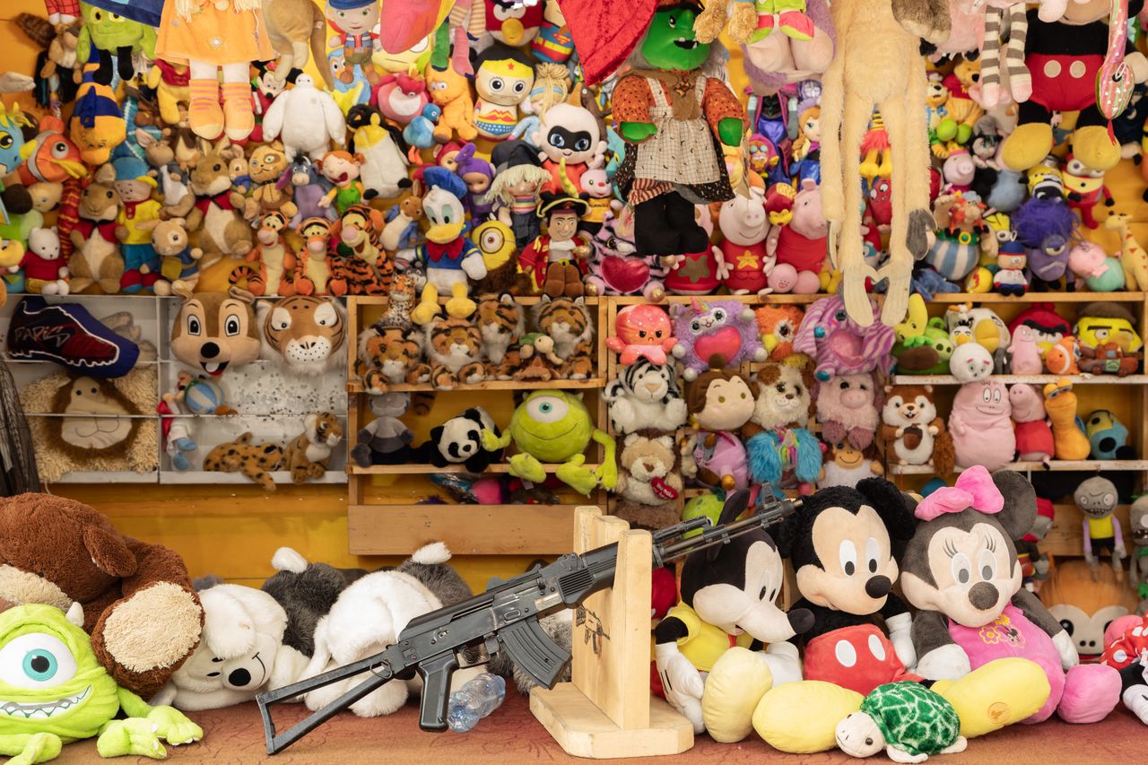 Peluches colorées et lots à gagner dans un stand de tir de fête foraine.