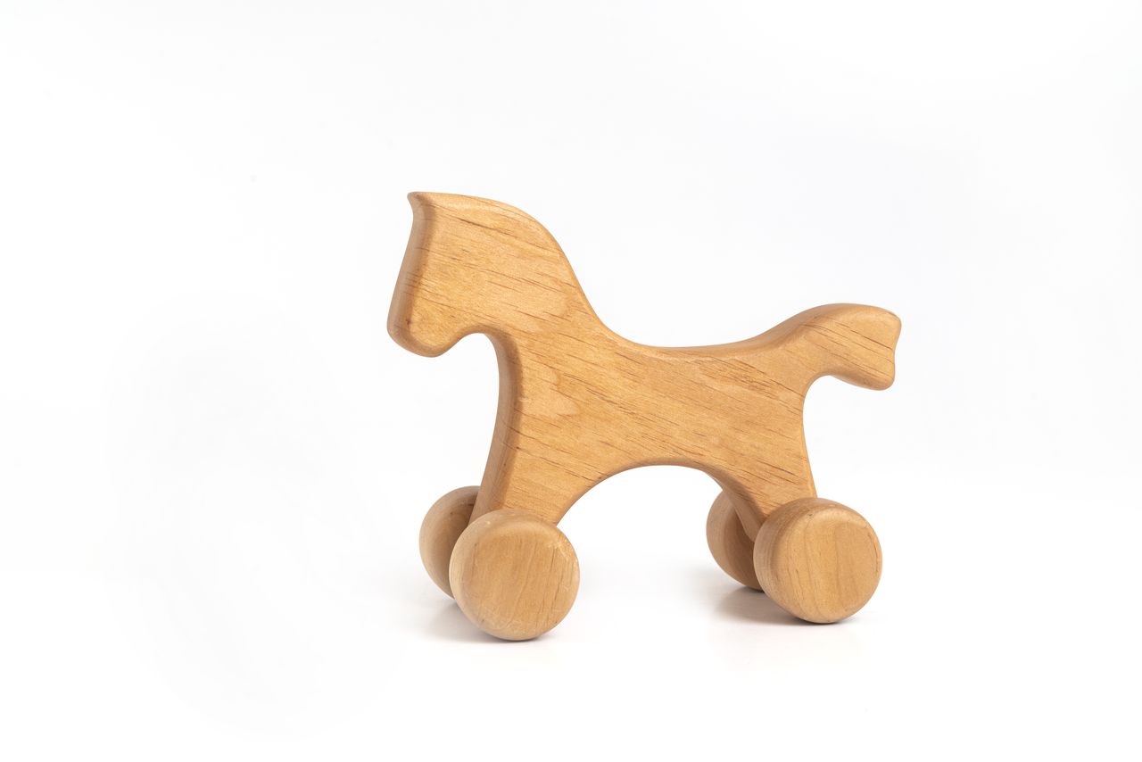 Cheval en bois brut sur roulettes, jouet à pousser fait main.