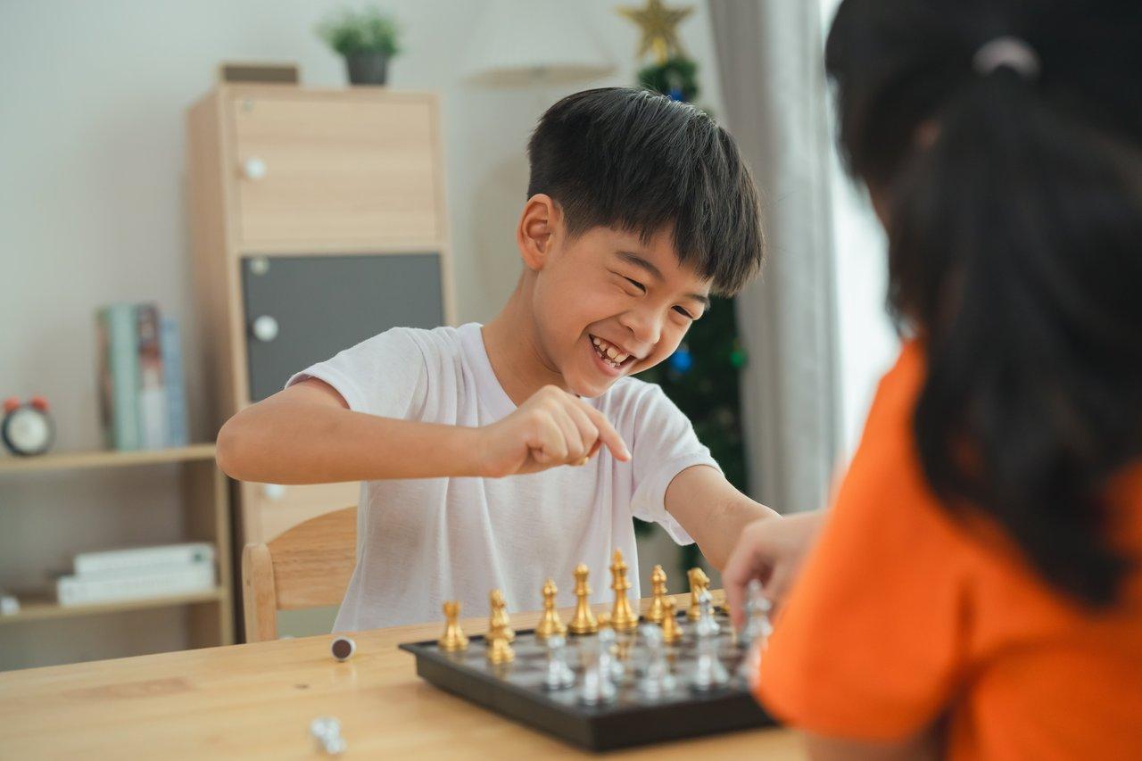 Deux enfants jouent à un jeu de société avec stratégie, illustrant l'interaction sociale et le draft ouvert.