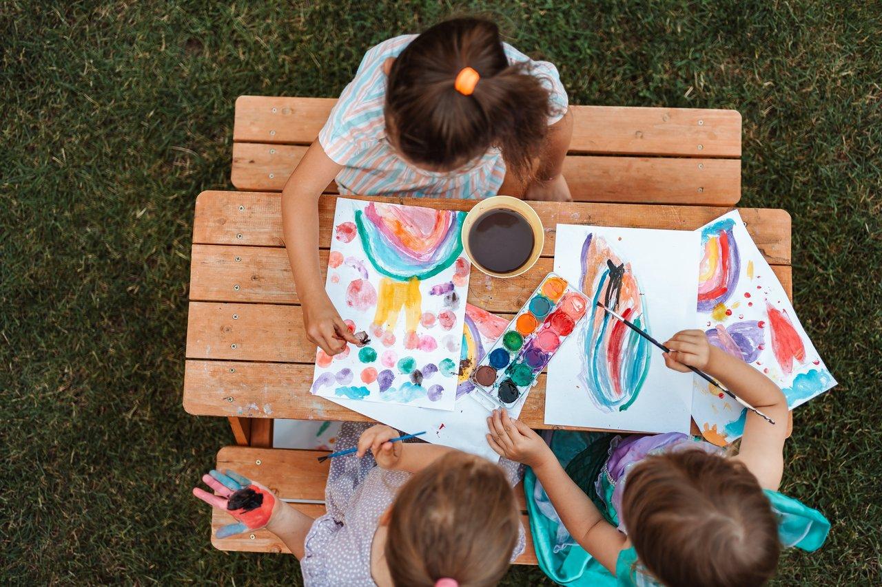 Enfants concentrés créant une fresque collective colorée lors d’un anniversaire d’enfants à la maison.