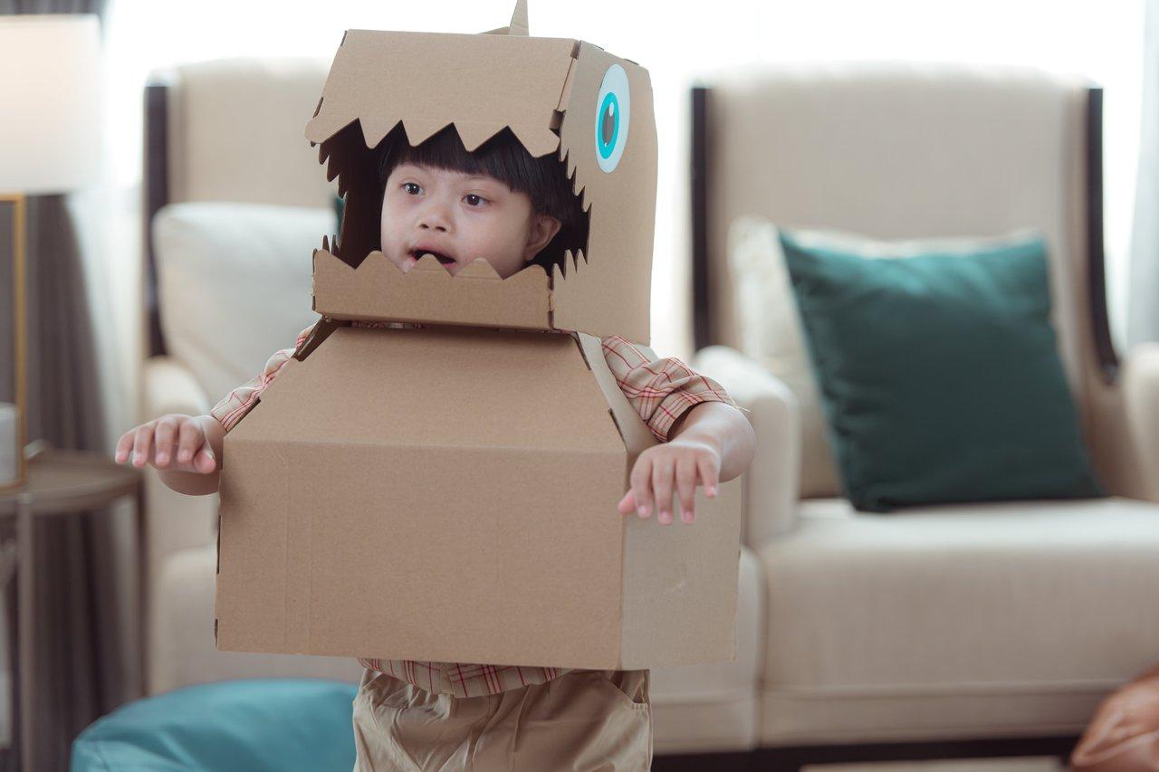 Un enfant concentré construisant un robot articulé en papier cartonné avec des outils Makedo.